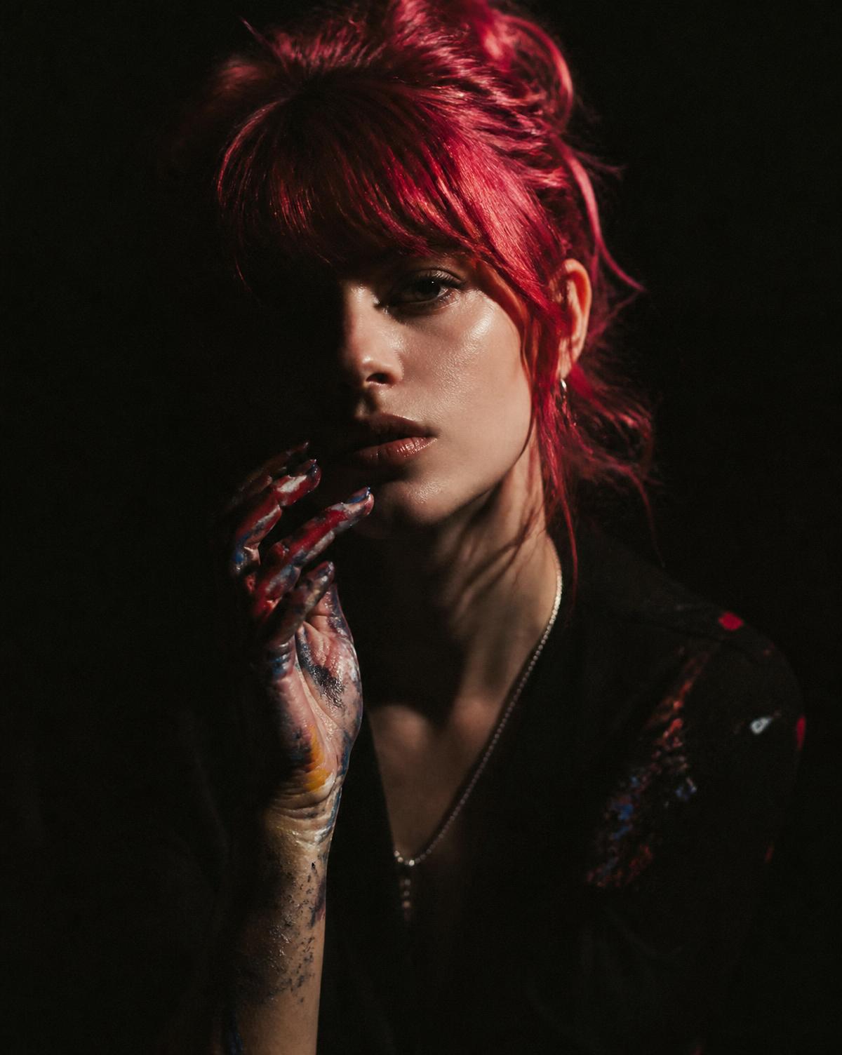 Editorial portrait of VENOM, artist, in shadow with red hair